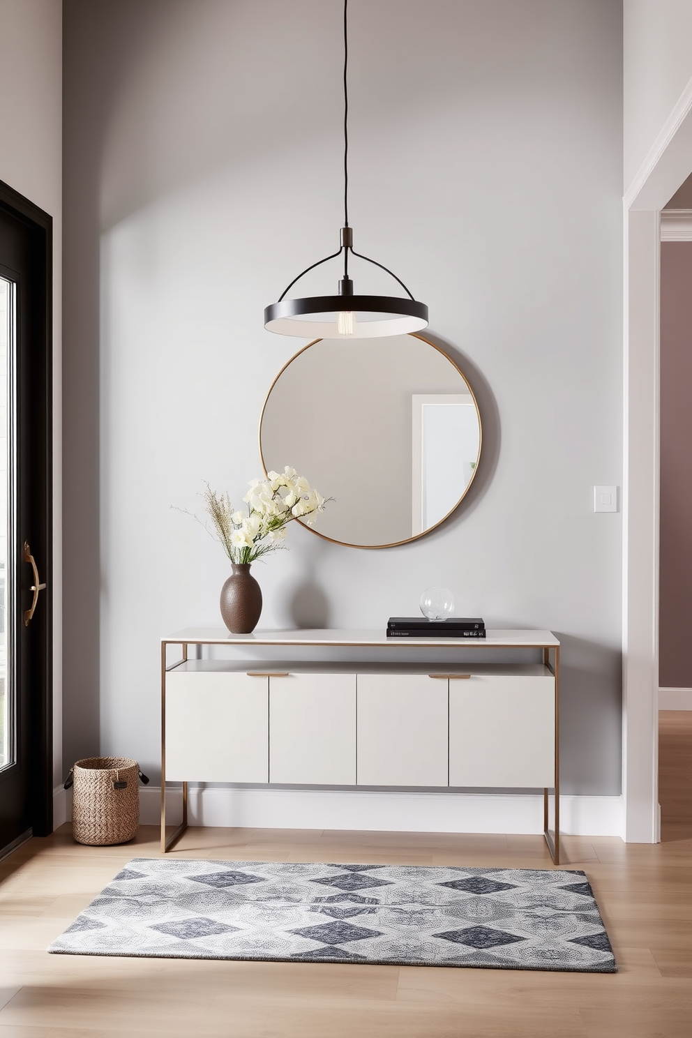 A stunning entryway featuring a sleek hanging pendant light that adds a modern touch. The space is adorned with a minimalist console table against the wall, complemented by a large round mirror above it. The walls are painted in a soft gray hue, creating an inviting atmosphere. A stylish area rug lies beneath the table, adding warmth and texture to the entryway.