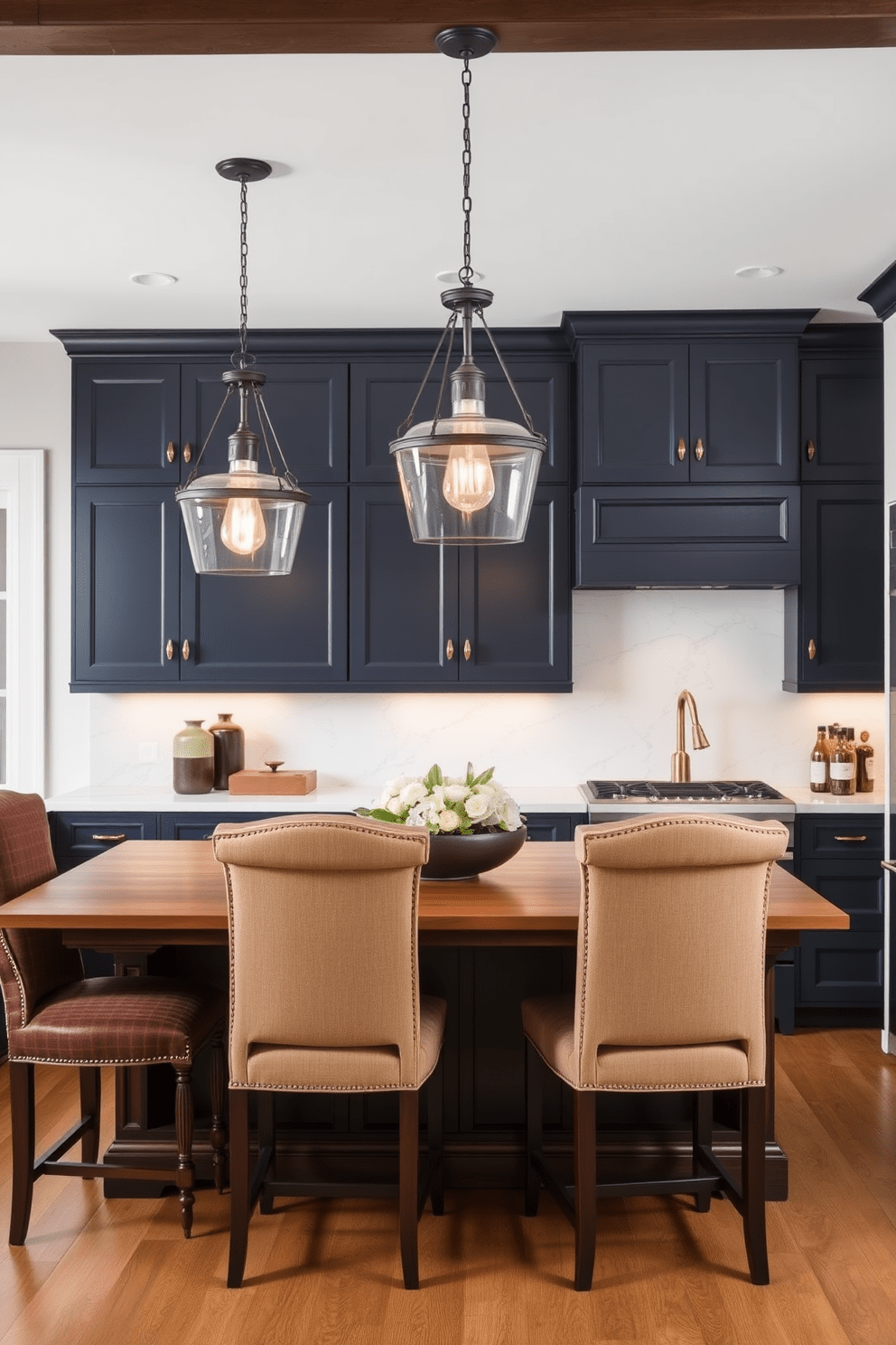 A traditional kitchen design featuring elegant lighting fixtures that blend classic charm with modern aesthetics. The space includes a large wooden island with intricate detailing, surrounded by high-backed chairs upholstered in a rich fabric. Above the island, a pair of vintage-inspired pendant lights with contemporary finishes provide warm illumination. The cabinetry is a mix of deep navy blue and crisp white, complemented by a sleek marble backsplash and polished brass hardware.