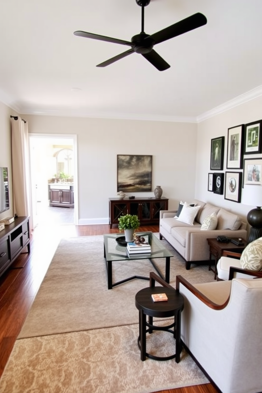 A transitional living room that seamlessly blends traditional and modern elements. The space features a comfortable sectional sofa in a neutral fabric, paired with a sleek glass coffee table and a pair of accent chairs in a rich, dark wood finish. A large area rug anchors the seating arrangement, providing warmth and texture. On one wall, a stylish media console holds a flat-screen television, while the opposite wall showcases a gallery of framed art in various sizes for an eclectic touch.