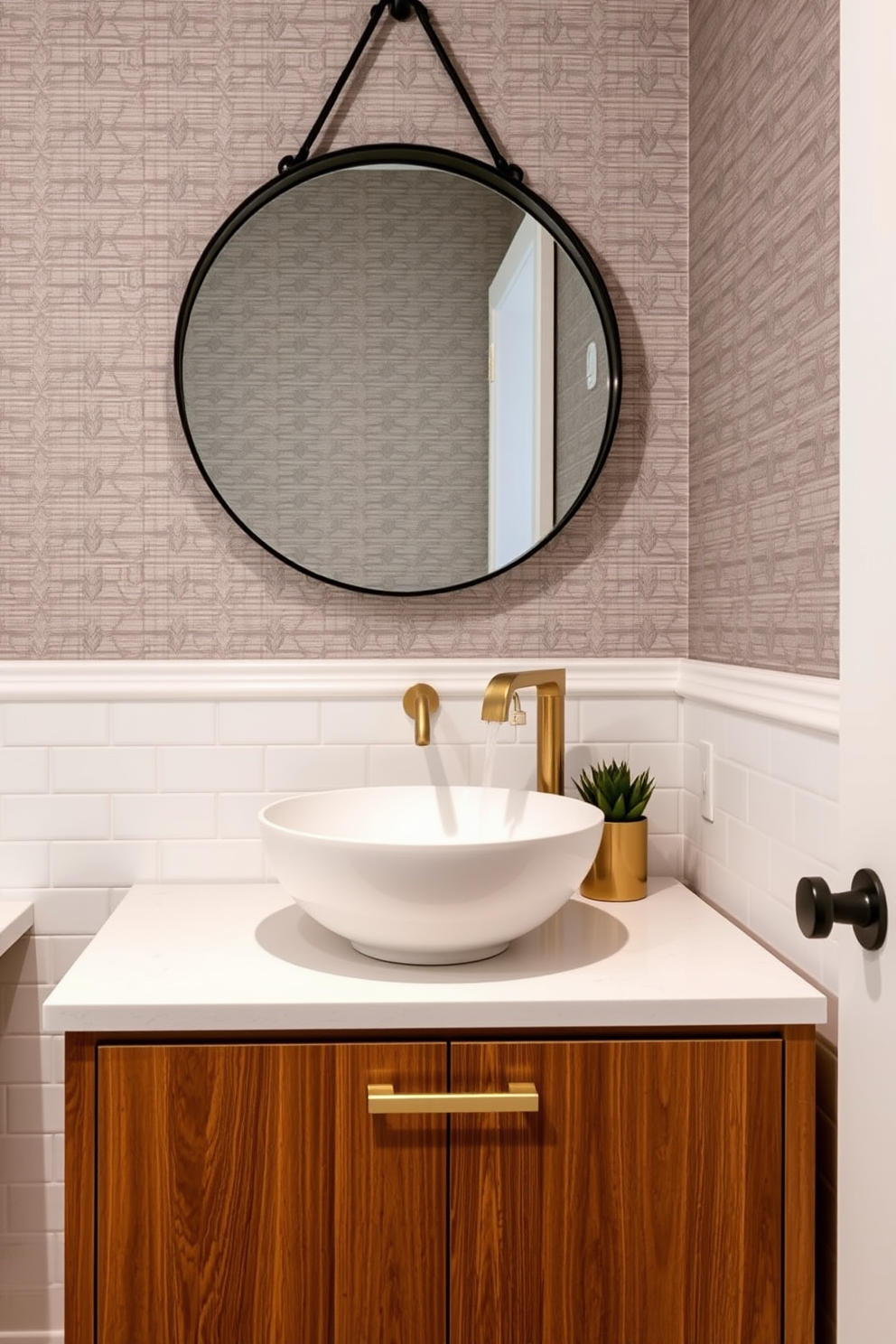 A stylish vessel sink is the focal point of this trendy powder room. It sits atop a sleek wooden vanity with a rich finish, complemented by modern brass fixtures. The walls are adorned with a chic wallpaper featuring a subtle geometric pattern. A round mirror with a thin black frame hangs above the sink, enhancing the room's contemporary aesthetic.