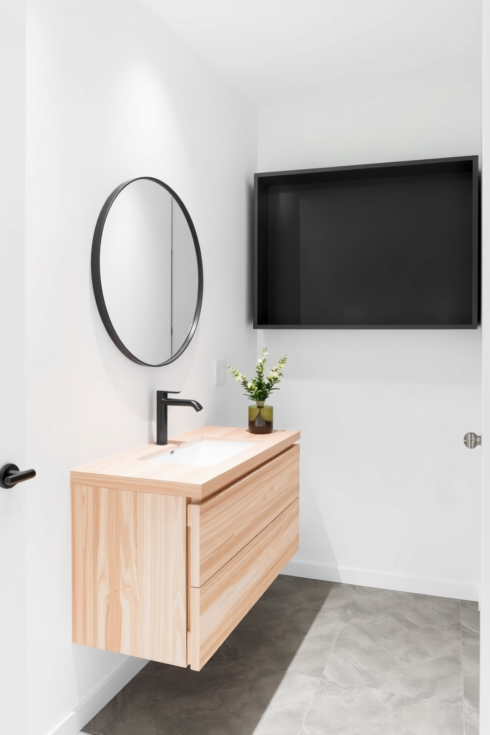 A minimalist powder room featuring clean lines and a sleek floating vanity made of light wood. The walls are painted in a soft white, and the floor is adorned with large grey tiles for a contemporary look. A round mirror with a thin black frame hangs above the vanity, reflecting a stylish pendant light. To add a touch of warmth, a small potted plant sits on the countertop next to a neatly folded hand towel.