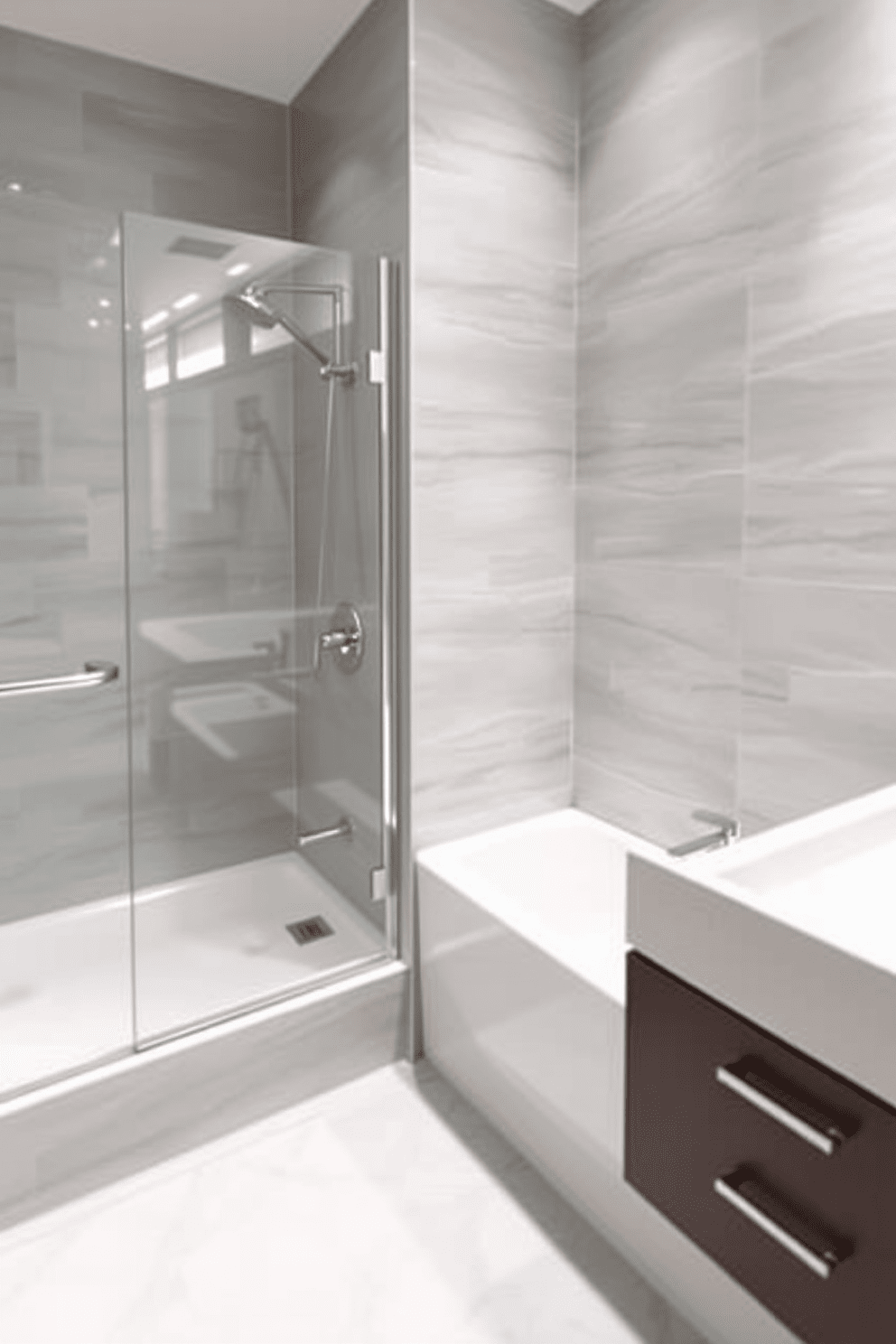 A contemporary bathroom featuring a tub shower combo with sleek chrome fixtures that add a modern touch. The walls are adorned with large format tiles in a soft gray color, while the floor showcases a subtle geometric pattern in white and light gray.