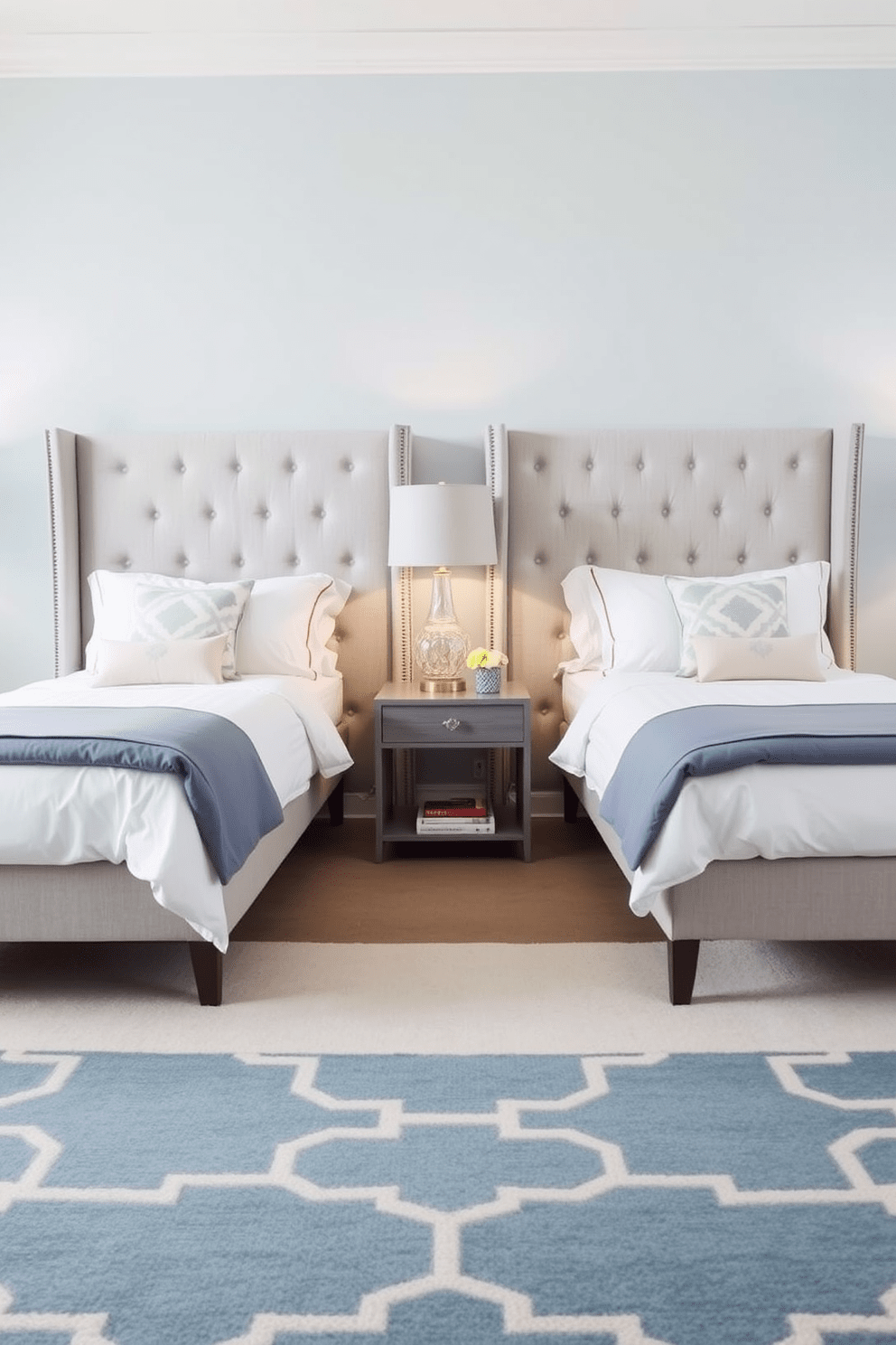 A twin bedroom featuring a shared headboard that creates a sense of unity between the two beds. The headboard is upholstered in a soft gray fabric, complementing the light blue walls and providing a cohesive look to the space. Each bed is dressed in matching white linens with decorative throw pillows in pastel colors. A stylish area rug in a geometric pattern anchors the room, while a shared nightstand between the beds holds a decorative lamp and a few books.