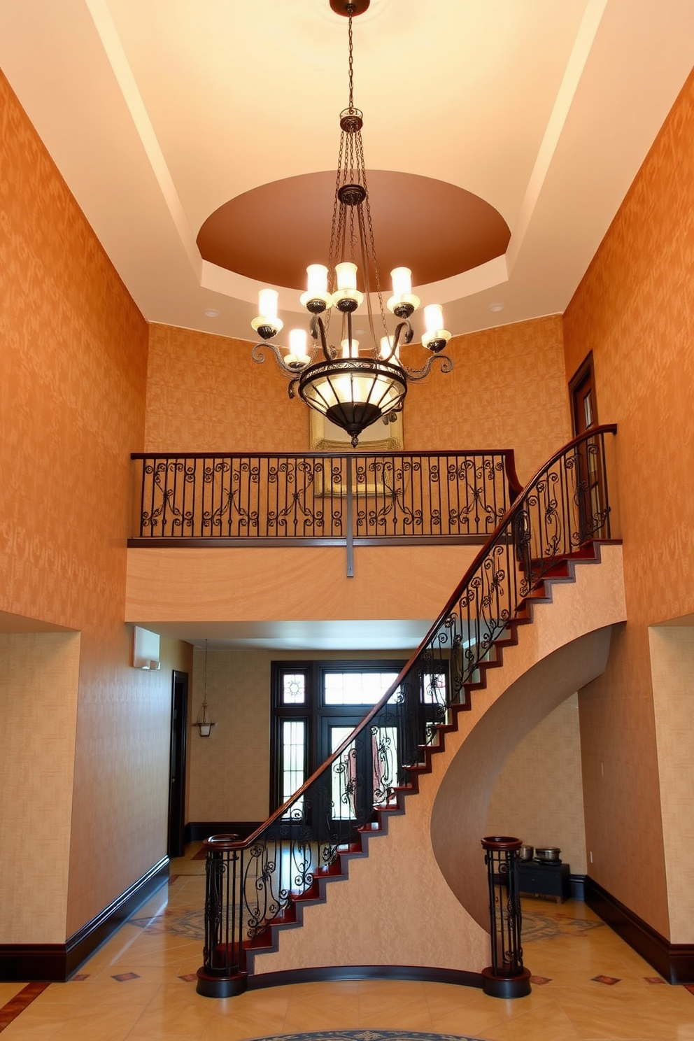 A grand chandelier hangs elegantly from the ceiling, casting a warm glow over the spacious two-story foyer. The walls are adorned with rich, textured wallpaper, and a stunning staircase with intricate wrought iron railings leads to the upper level.