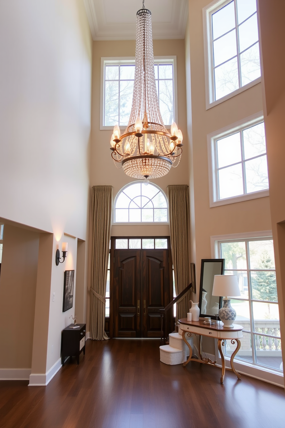 Layered lighting creates a warm and inviting ambiance in a two story foyer. A stunning chandelier hangs from the high ceiling, complemented by wall sconces that provide soft illumination along the staircase. The foyer features a grand entrance with a large double door and expansive windows that allow natural light to flood the space. Elegant artwork adorns the walls, and a stylish console table is placed against one side, topped with decorative accents and a statement mirror.