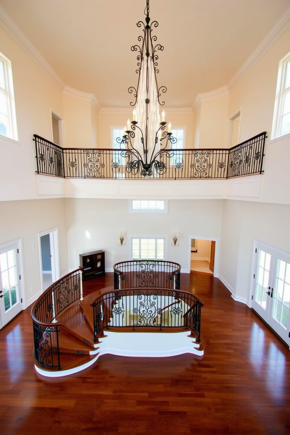 A grand two story foyer featuring a sweeping staircase with elegant wrought iron railings. The ceiling is adorned with a stunning chandelier that cascades light down into the space. The walls are painted in a soft cream color, complemented by rich hardwood flooring that adds warmth. Large windows on either side allow natural light to flood the area, creating an inviting atmosphere.