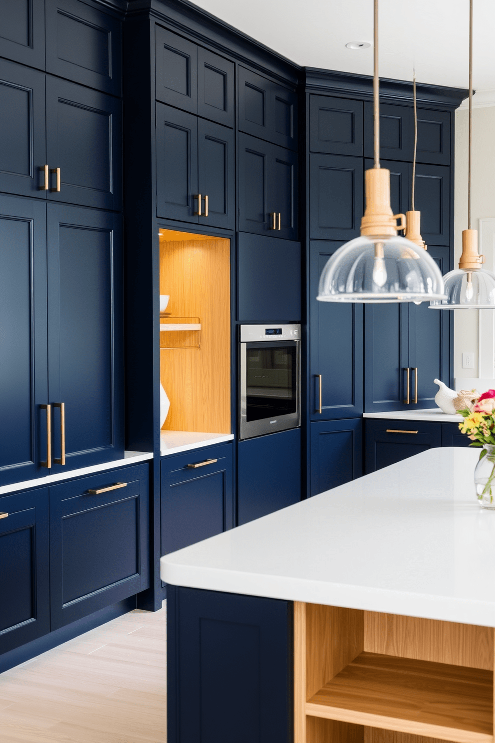 A deep navy kitchen with light oak highlights creates a stunning contrast. The cabinetry features deep navy doors paired with light oak accents on the island and shelving. The countertops are a sleek white quartz, providing a bright and airy feel. Pendant lights with a modern design hang above the island, adding both functionality and style.