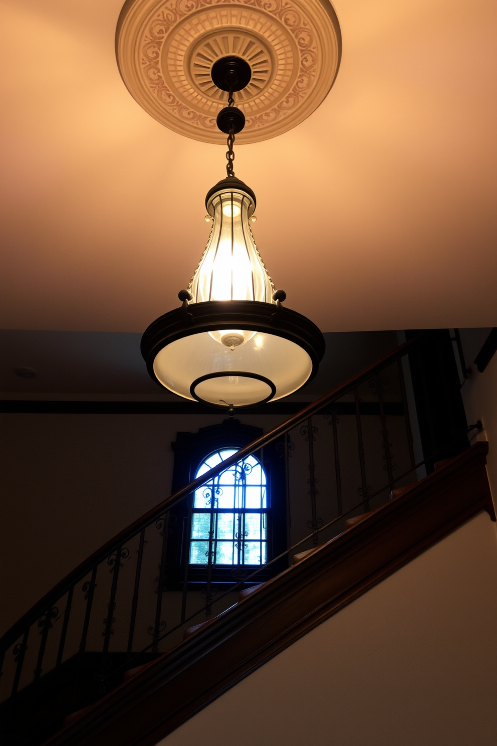 A vintage light fixture hangs gracefully from the ceiling illuminating the room with a warm glow. The fixture features intricate details and a classic design that adds character to the space. The vintage staircase showcases elegant craftsmanship with ornate railings and rich wooden steps. Its design creates a stunning focal point while maintaining a timeless appeal throughout the home.