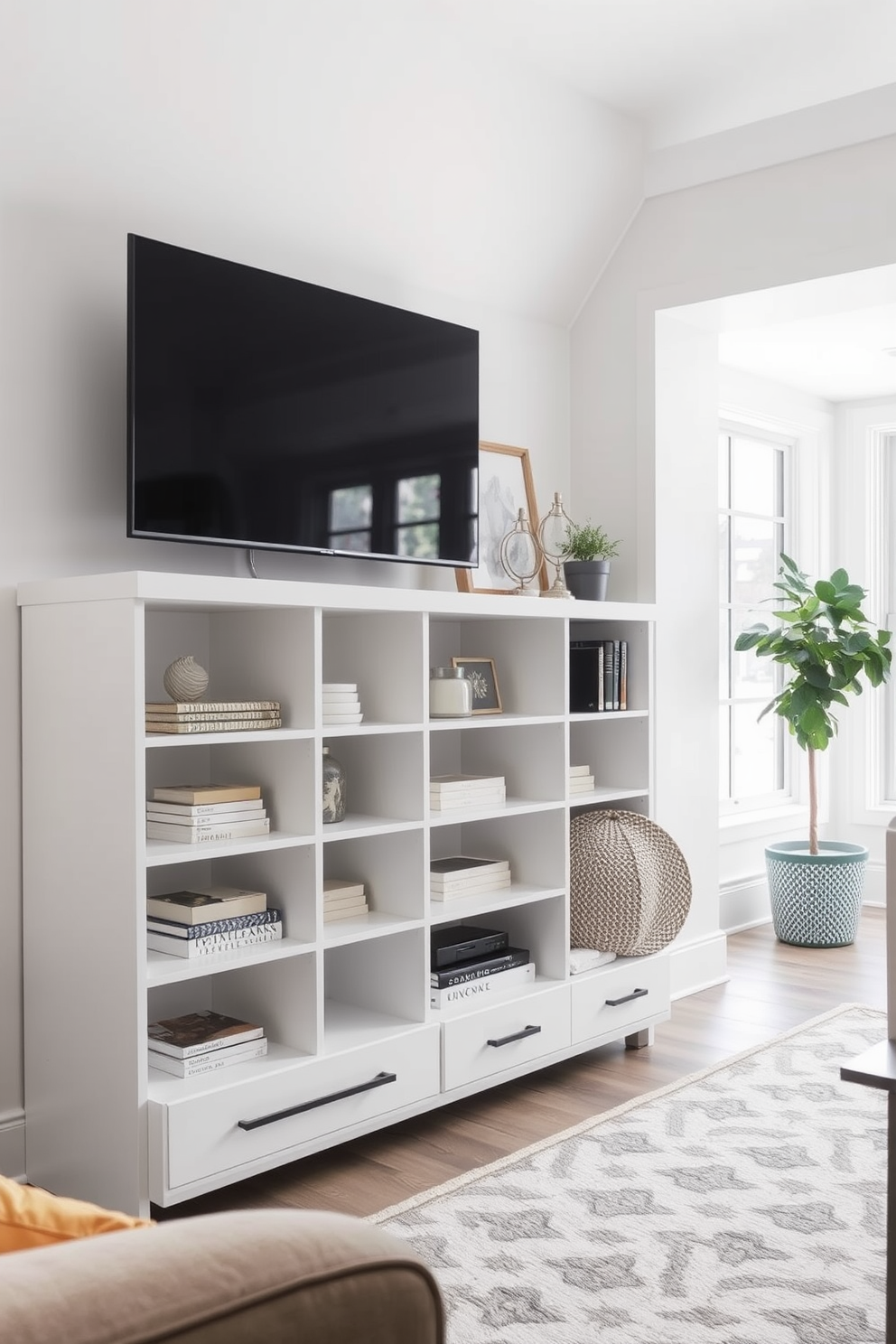 A white entertainment center sits against the wall, featuring multiple shelves for organized media storage. The center is complemented by a sleek television mounted above and decorative items neatly arranged on the shelves. The basement design showcases a bright and airy space with white walls and large windows allowing natural light to flood in. Cozy seating arrangements and a stylish rug create an inviting atmosphere perfect for relaxation and entertainment.