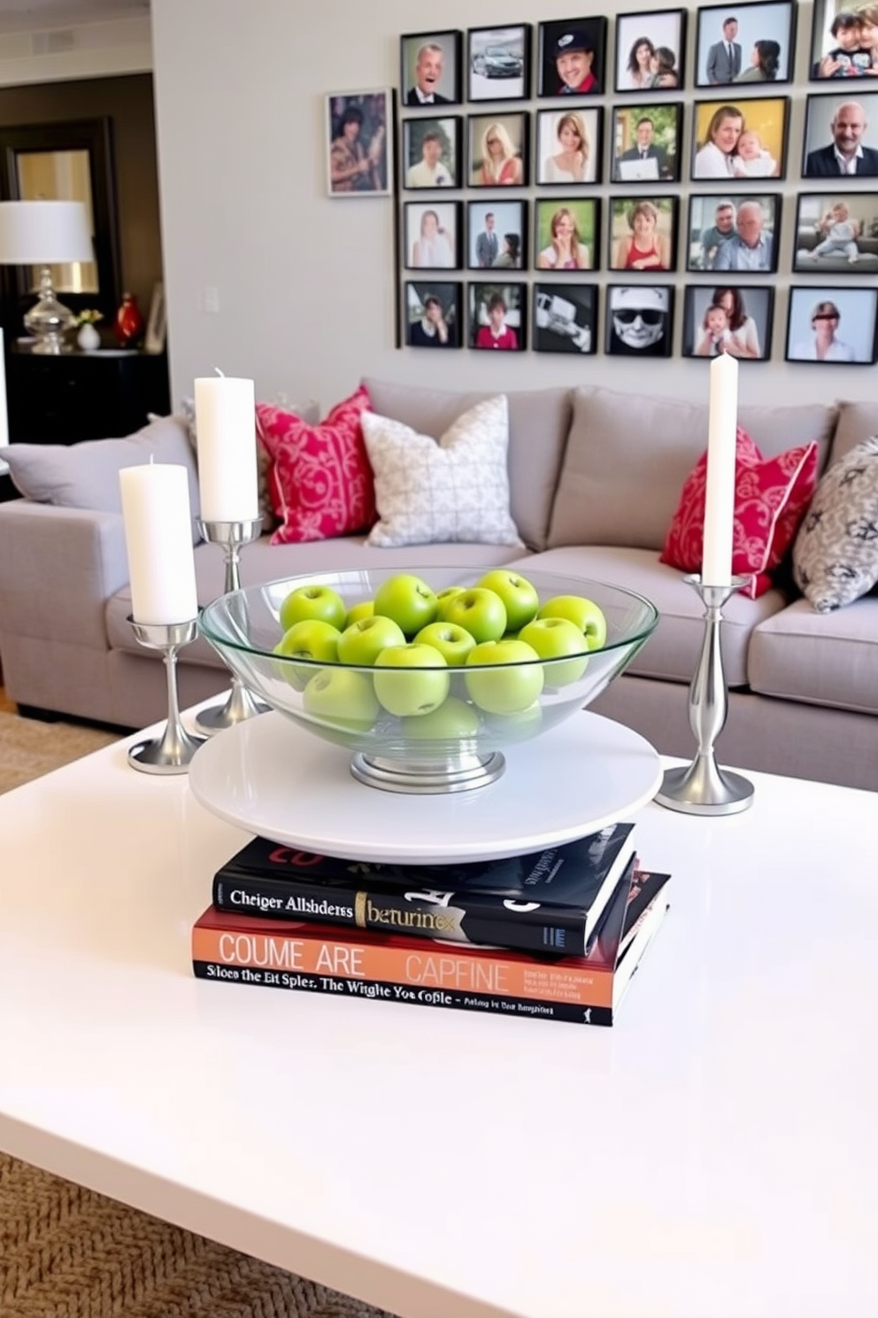 An elegant white coffee table centerpiece features a large decorative bowl filled with fresh green apples and a stack of stylish coffee table books. Surrounding the centerpiece are two sleek candle holders with white candles, adding a touch of warmth to the space. The family room design showcases a comfortable sectional sofa in soft gray upholstery, paired with vibrant throw pillows for a pop of color. A large area rug anchors the seating area, while a gallery wall of family photos adds a personal touch to the inviting atmosphere.