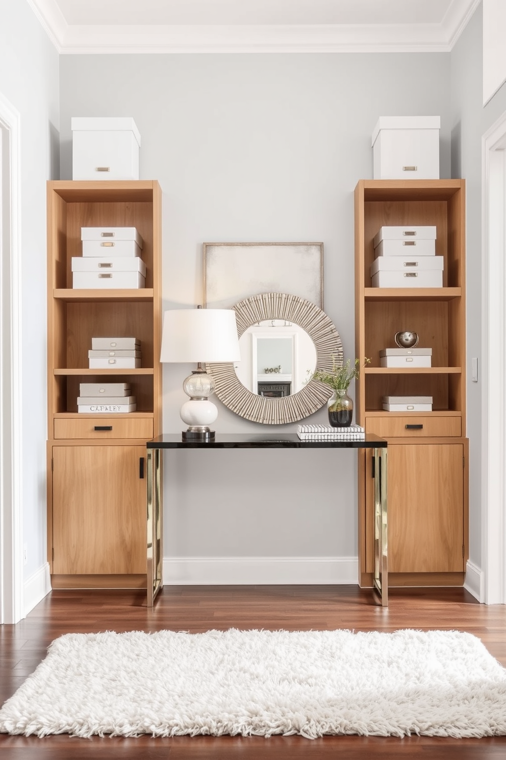 Open shelving adorned with white decorative boxes creates a clean and organized look. The shelves are complemented by a soft gray wall that enhances the brightness of the space. In the foyer, a sleek console table is positioned against the wall, topped with a stylish lamp and a decorative mirror. A plush area rug in neutral tones anchors the space, adding warmth and texture.