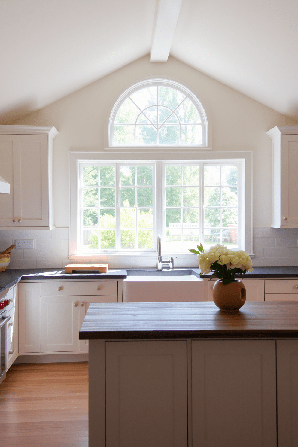 A bright and airy kitchen features a large farmhouse sink situated under a spacious window that allows natural light to flood the room. The cabinets are painted in a soft white, complemented by a rustic wooden island that adds warmth and charm to the overall design.