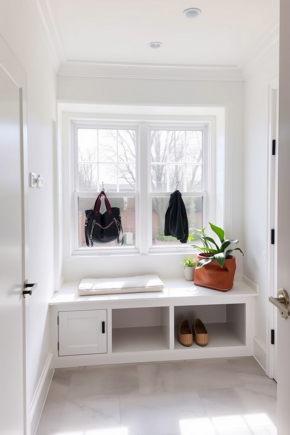 A bright and airy mudroom featuring a large window that allows natural light to flood the space. The walls are painted in a crisp white, complemented by a built-in bench with storage underneath and hooks above for coats and bags. The floor is adorned with light gray tiles that add a touch of elegance. Potted plants are placed near the window, bringing a fresh and inviting feel to the room.