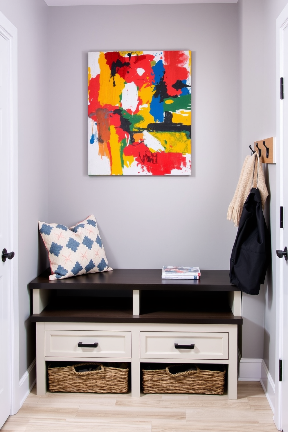 Bright artwork to liven up the space. The mudroom features a functional bench with storage underneath and hooks for coats on the wall. The walls are painted in a soft gray to create a neutral backdrop. A colorful abstract painting hangs prominently above the bench, adding vibrancy and personality to the area.