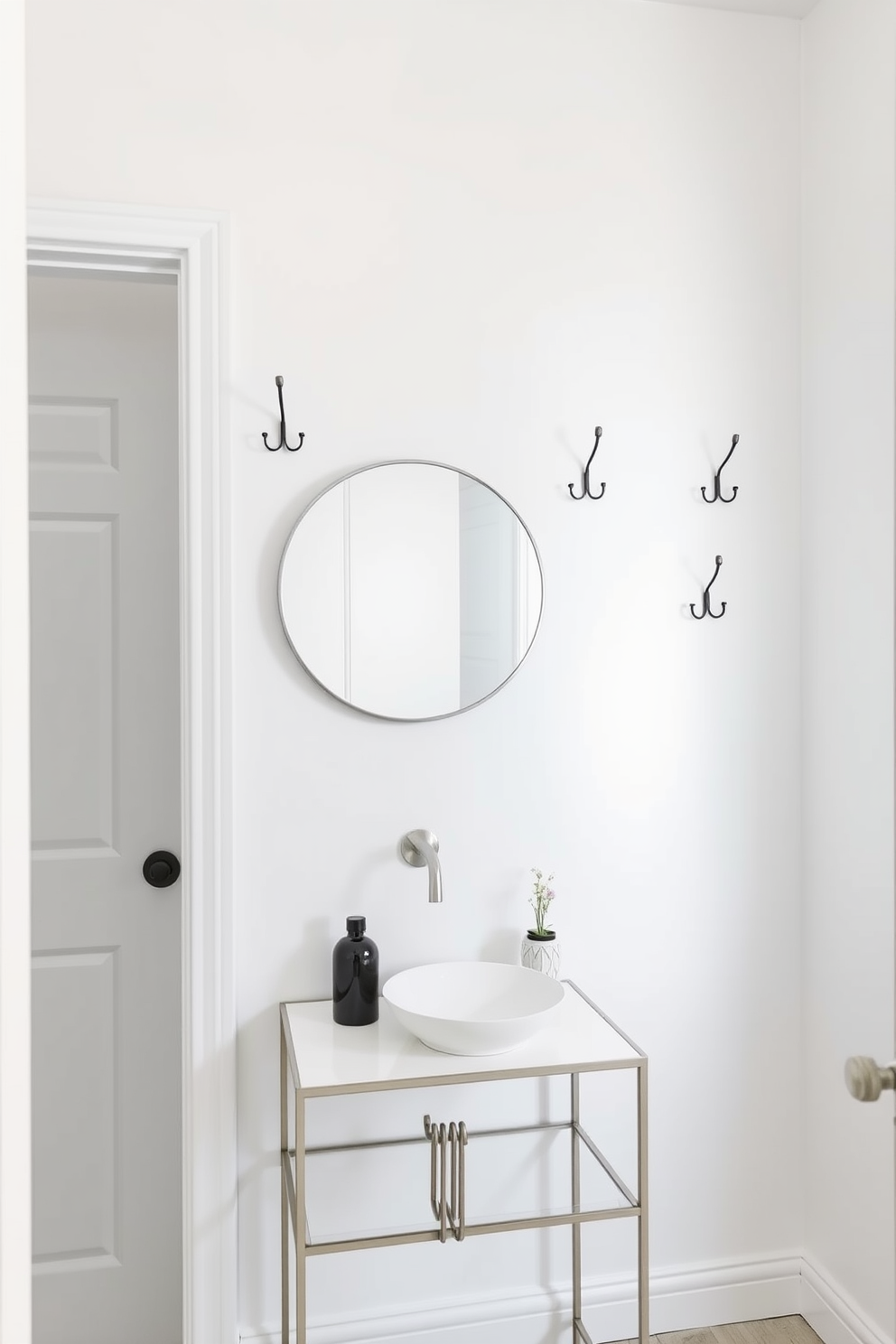 Stylish hooks for functional wall decor. The white powder room features a sleek design with minimalist hooks mounted on the wall, providing both practicality and aesthetic appeal. The walls are painted in a crisp white, creating a bright and airy atmosphere. A small round mirror hangs above a chic console table, adorned with decorative items that complement the overall decor.