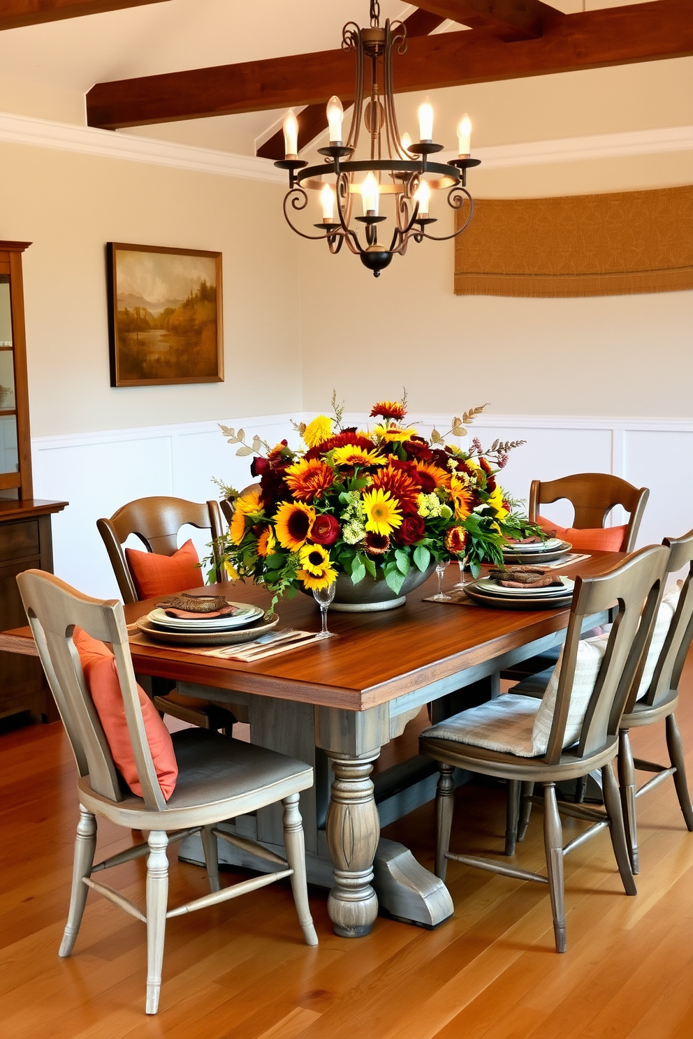 A warm and inviting dining room featuring a rustic wooden table set for a fall gathering. Surrounding the table are mismatched chairs, each adorned with cozy cushions in autumn hues. On the table, a stunning floral arrangement showcases vibrant sunflowers and rich dahlias, complemented by seasonal foliage. Soft, ambient lighting from a chandelier above enhances the cozy atmosphere, creating a perfect setting for family and friends to enjoy a meal together.