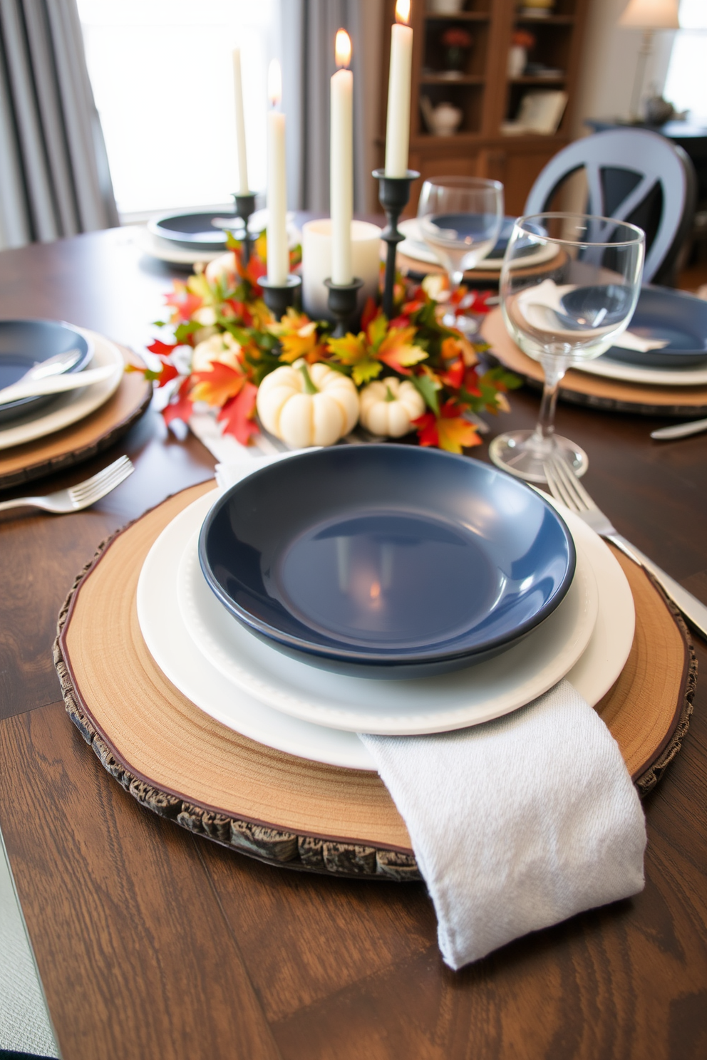 A curated table setting features layered plates in varying sizes and textures. The base layer is a rustic wooden charger, topped with a deep navy dinner plate and a delicate white salad plate. Incorporate seasonal elements like small pumpkins and colorful leaves for a fall touch. Soft, warm lighting from a centerpiece candle arrangement adds an inviting ambiance to the dining room.