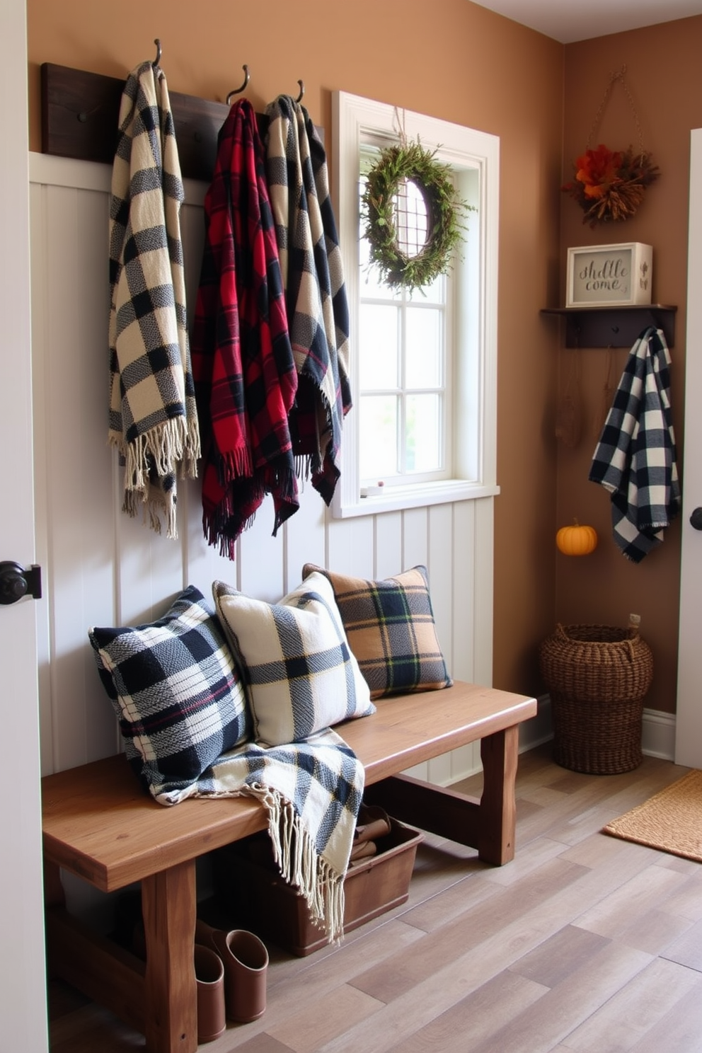 A cozy mudroom adorned with warm plaid throw blankets casually draped over a rustic wooden bench. The walls are painted in soft earth tones, and a collection of autumn-themed decor adds a welcoming touch to the space.