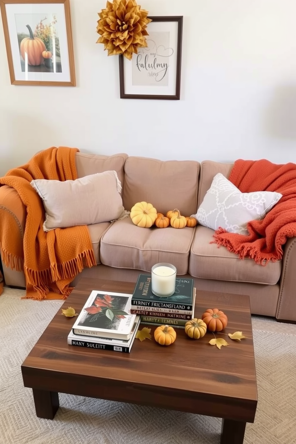 A cozy living room setting featuring a plush sofa adorned with soft throw blankets in warm autumn colors. The space is accented with seasonal decor, including small pumpkins and golden leaves, creating an inviting atmosphere for fall. In this small space, a carefully arranged coffee table sits in front of the sofa, topped with a stack of books and a scented candle. The walls are adorned with framed artwork that reflects the fall theme, enhancing the overall warmth of the room.