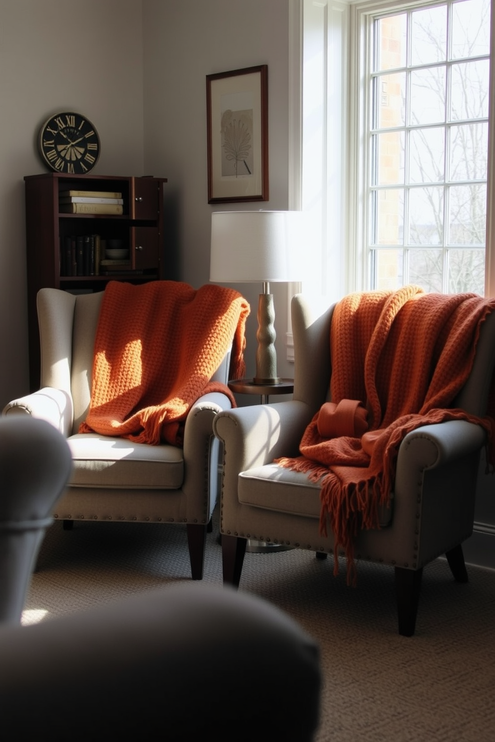 Accent chairs are placed in a small living area, adorned with cozy throws in warm autumn colors. The chairs are positioned near a window, allowing natural light to illuminate the space while creating an inviting atmosphere.