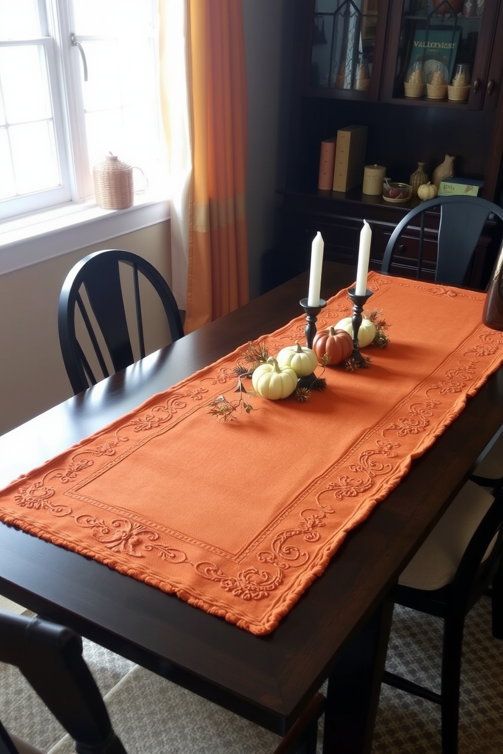 A cozy dining setting featuring warm-toned table runners that complement the autumn season. The table is adorned with seasonal decorations like small pumpkins and candles to create an inviting atmosphere. The dining area is designed to maximize a small space while maintaining elegance. Soft lighting from a nearby window enhances the warmth of the table runners and the overall decor.