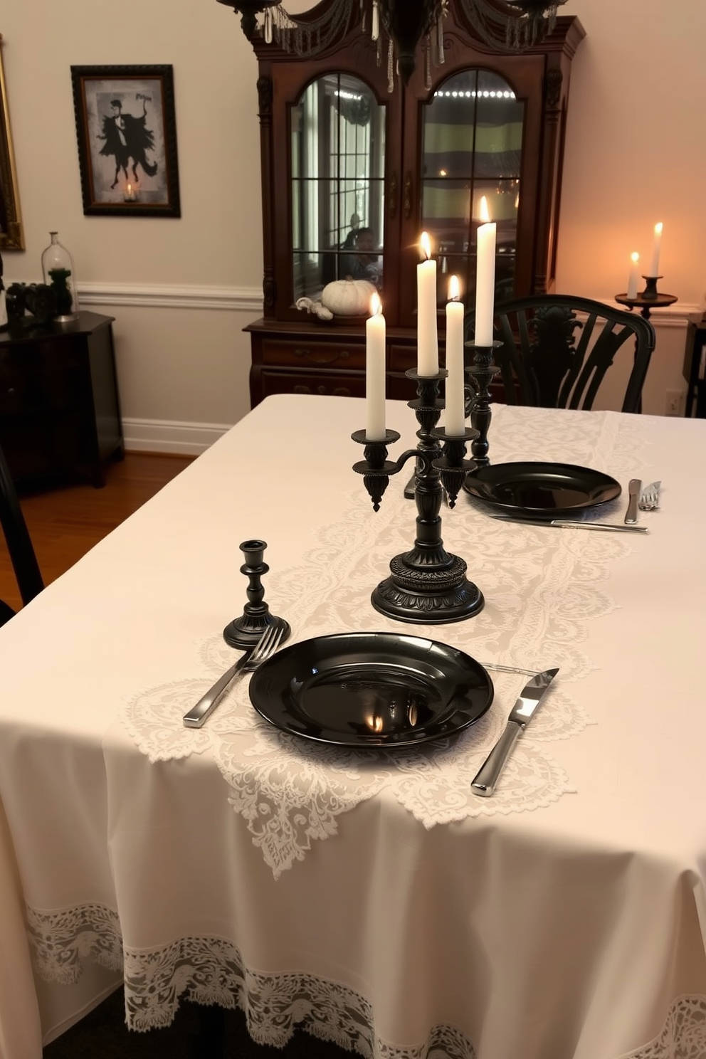 A dining room elegantly decorated for Halloween features a ghostly white tablecloth adorned with a delicate lace overlay. The table is set with black ceramic plates and silver cutlery, while flickering candles in ornate holders create a warm, inviting glow.