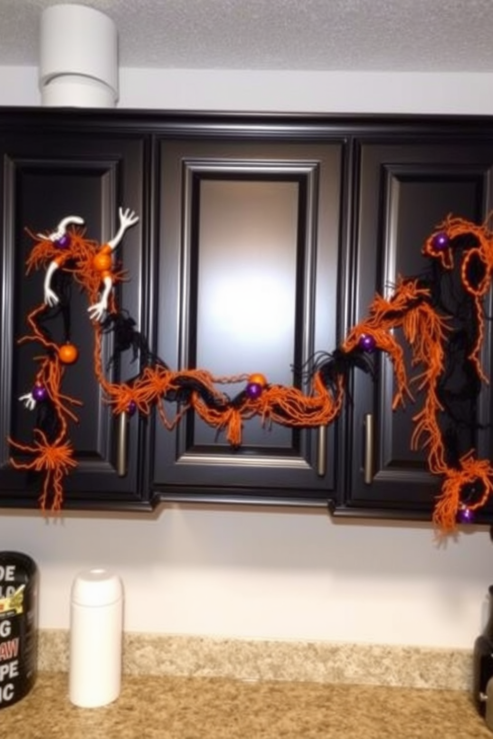 Ghoulish garlands are draped over the cabinets, adding a spooky touch to the kitchen. The cabinets are painted in a deep black color, contrasting with the bright orange and purple decorations of the garlands.