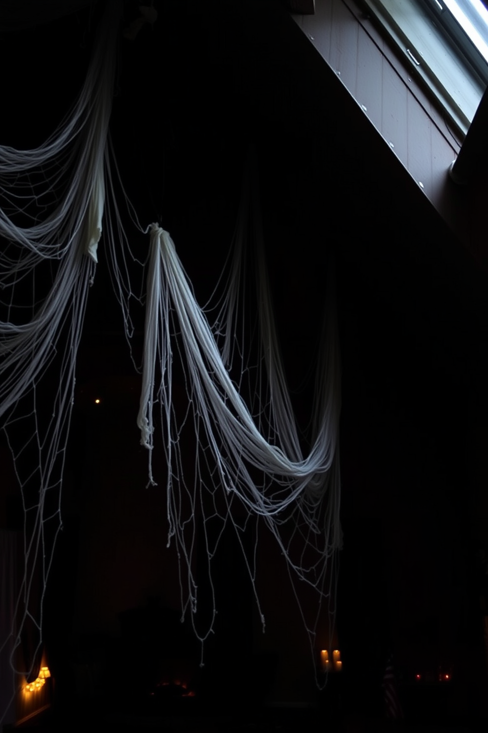 A spooky loft decorated for Halloween features creepy cobwebs draped in the corners of the room. Dim lighting casts eerie shadows across the walls, enhancing the haunting atmosphere of the space.