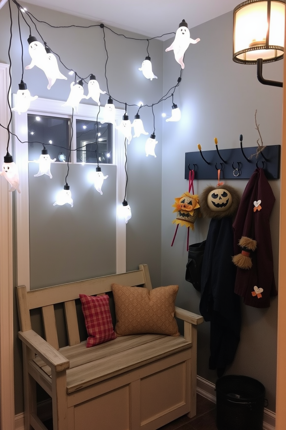 A cozy mudroom adorned with hanging ghost lights creating a spooky ambiance for Halloween. The space features a rustic bench with colorful cushions, and a wall-mounted coat rack displaying seasonal decorations.