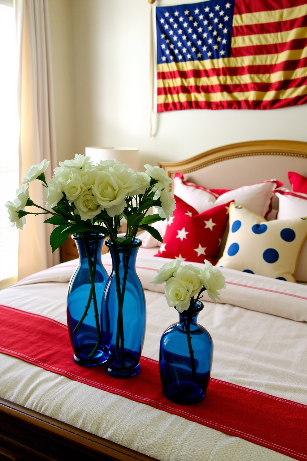 A cozy bedroom setting inspired by Independence Day. The room features a large bed draped in red white and blue linens with decorative pillows in star patterns. On the bedside table sit two elegant blue vases filled with fresh white flowers. A vintage American flag is artfully displayed on the wall adding a festive touch to the overall decor.