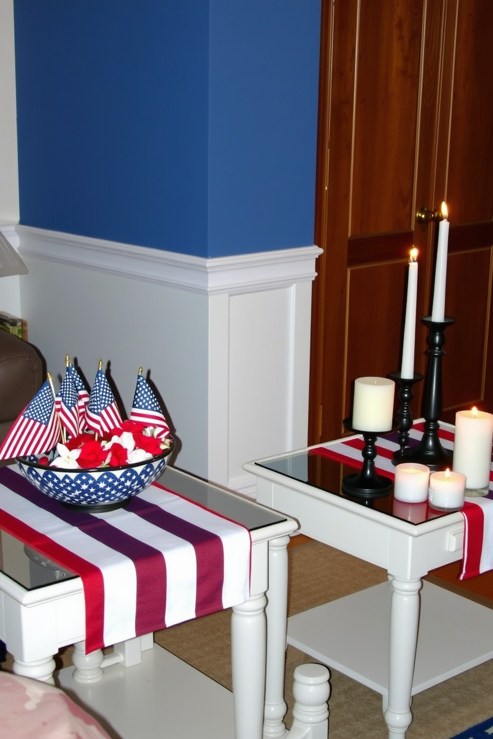 A vibrant living room setting for Independence Day. The side tables are adorned with a striped table runner in red, white, and blue, creating a festive atmosphere. On one table, there is a collection of small American flags and a decorative bowl filled with red and white flowers. The other table features a cozy arrangement of candles in varying heights, adding warmth to the celebration.