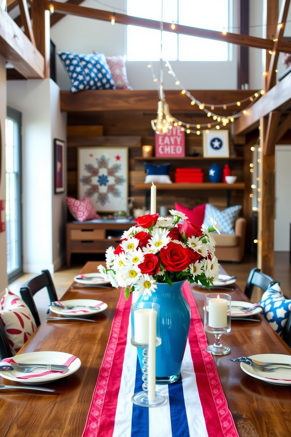 A festive Independence Day table setting features a long wooden table adorned with a vibrant red and white striped tablecloth. Centered on the table is a large blue vase filled with white daisies and red roses, surrounded by star-shaped candles. For Independence Day loft decorating ideas, the space showcases a mix of rustic and modern elements. Bold red, white, and blue accents are incorporated through throw pillows, wall art, and string lights draped across the beams.