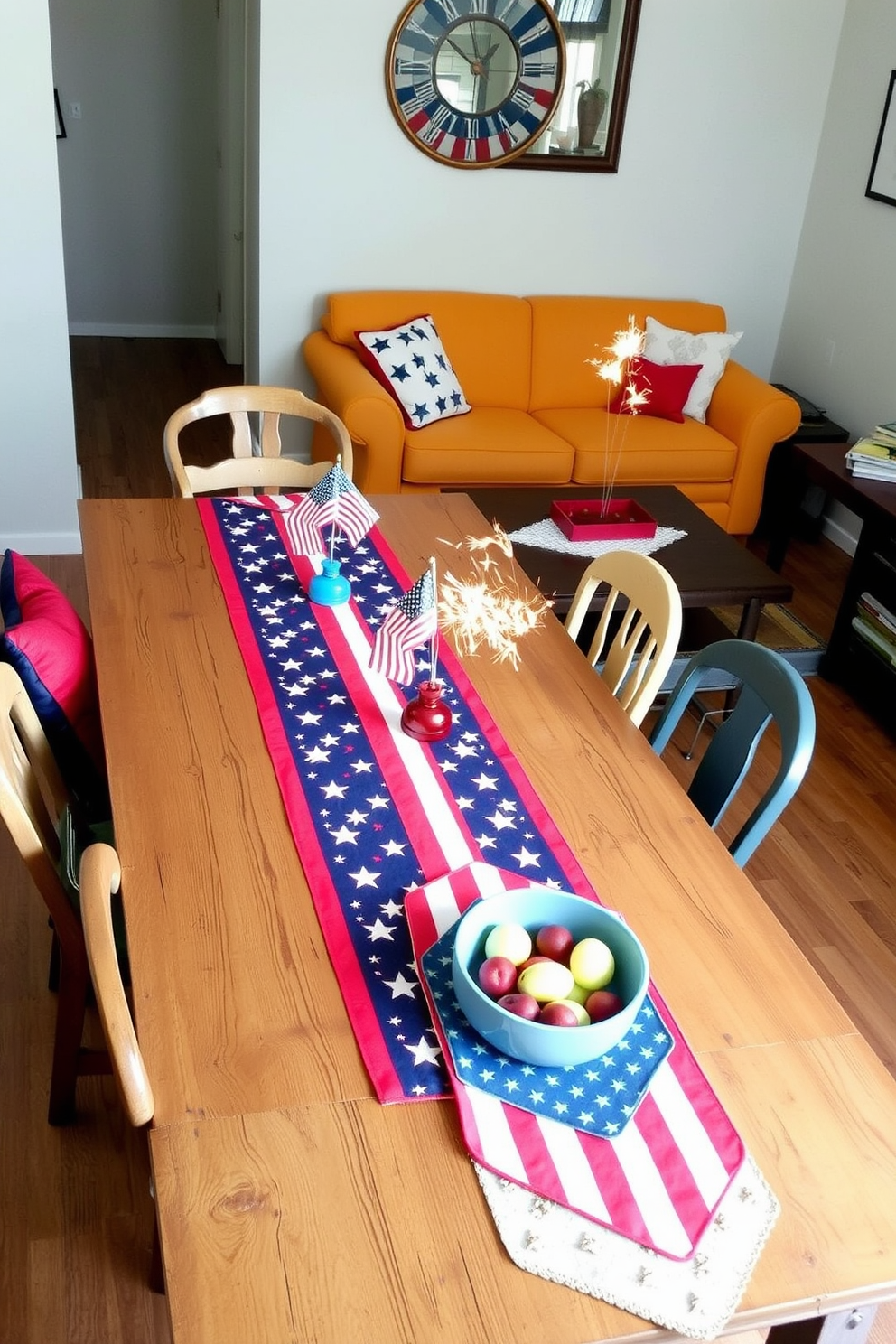 A vibrant table runner adorned with stars and stripes stretches across a rustic wooden dining table. Surrounding the table are mismatched chairs, each decorated with a small flag centerpiece to enhance the festive atmosphere. In a small living room, a cozy arrangement features a bright sofa with red and blue throw pillows. A coffee table is topped with a patriotic-themed table runner, complemented by a bowl of fresh fruit and a few sparklers for a touch of celebration.