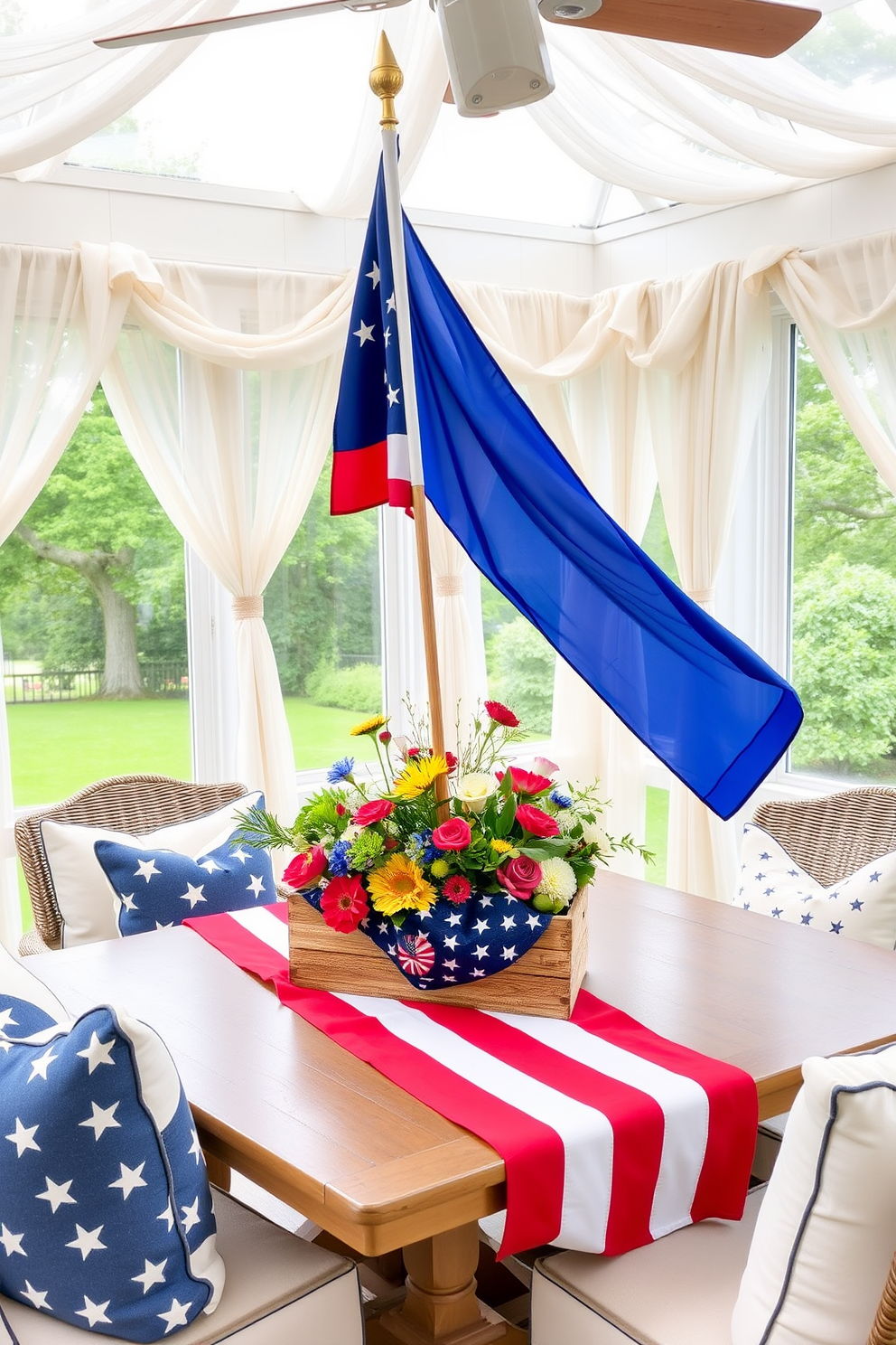 A patriotic themed table centerpiece featuring a vibrant red white and blue color scheme. The centerpiece includes a large flag draped elegantly across the table with an assortment of seasonal flowers in matching colors arranged in a rustic wooden box. The sunroom is decorated with light airy curtains that flutter gently in the breeze. Comfortable seating is arranged around the table with throw pillows showcasing stars and stripes patterns for a festive touch.