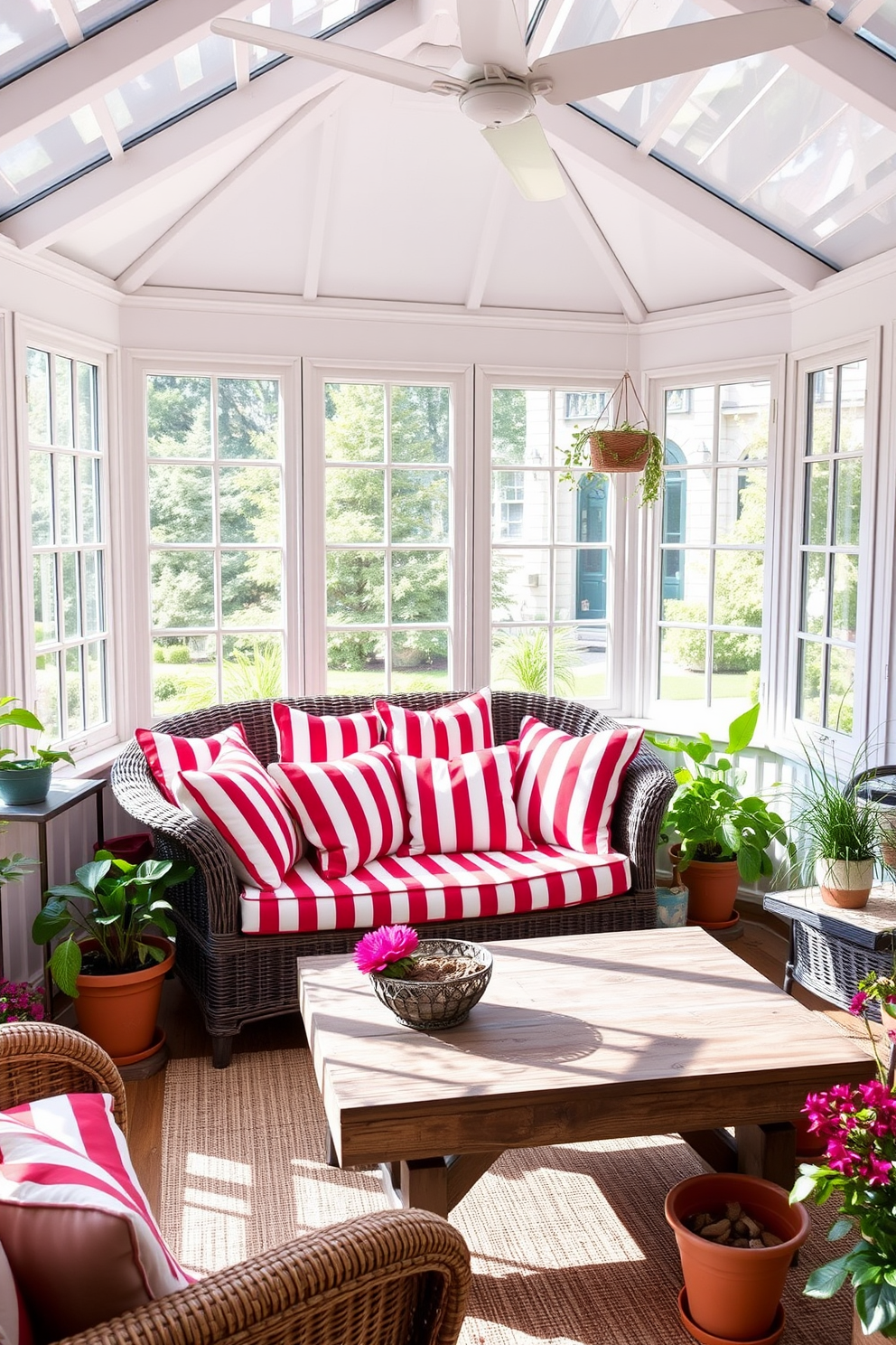 A sunroom filled with natural light features a cozy seating area adorned with red and white striped cushions. The cushions are arranged on a comfortable wicker sofa, complemented by a rustic wooden coffee table and vibrant potted plants around the space.