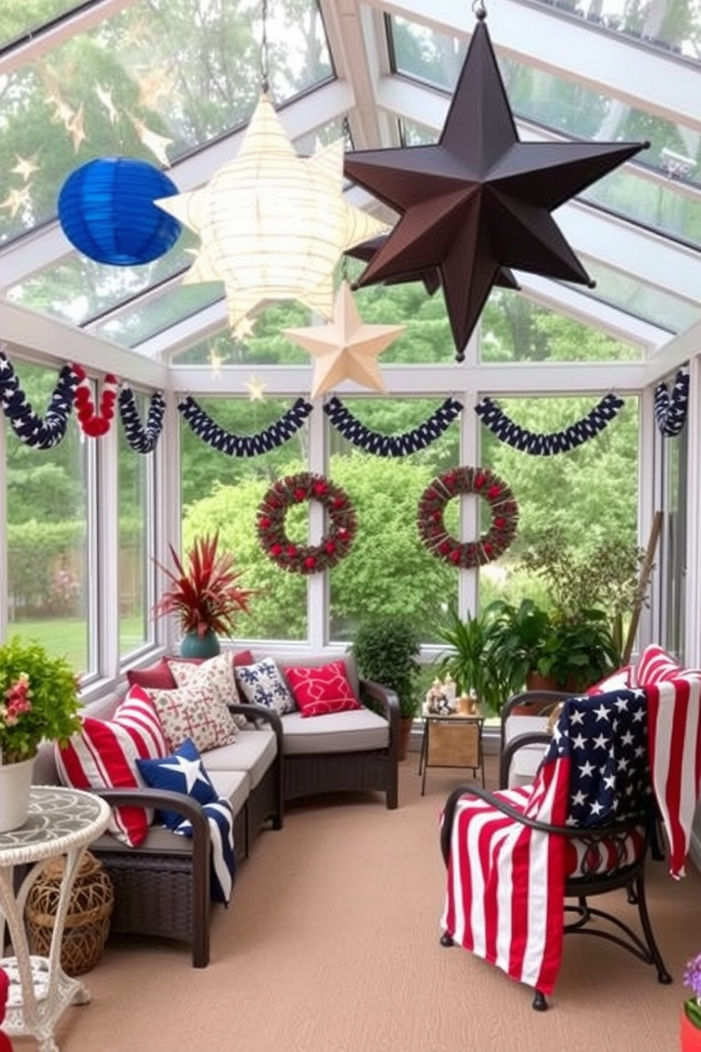 A sunroom decorated for Independence Day features star shaped lanterns hanging from the ceiling to create a festive ambiance. The space is filled with comfortable seating, adorned with red white and blue cushions and a large American flag draped over a nearby chair.