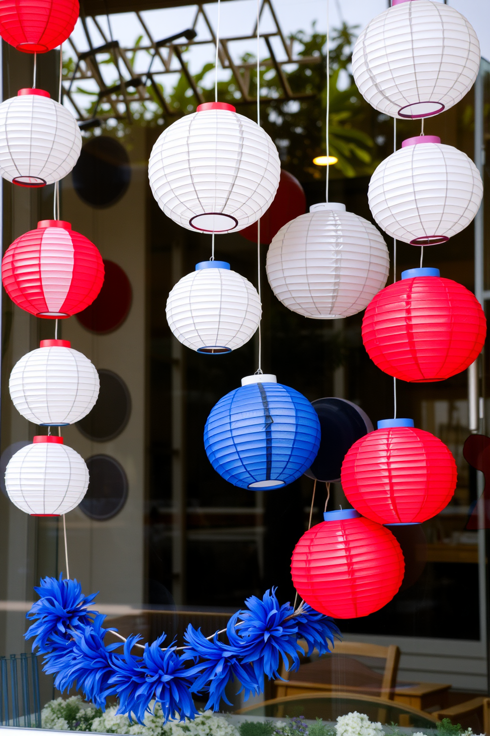 A festive window display adorned with hanging paper lanterns in red, white, and blue. The lanterns sway gently in the breeze, creating a cheerful atmosphere for Independence Day celebrations.