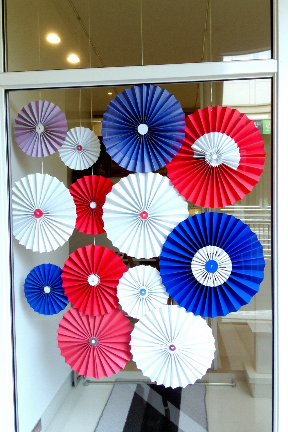 Create a festive window display for Independence Day featuring hanging red white and blue paper fans. The fans should be arranged in a visually appealing pattern to celebrate the holiday spirit.