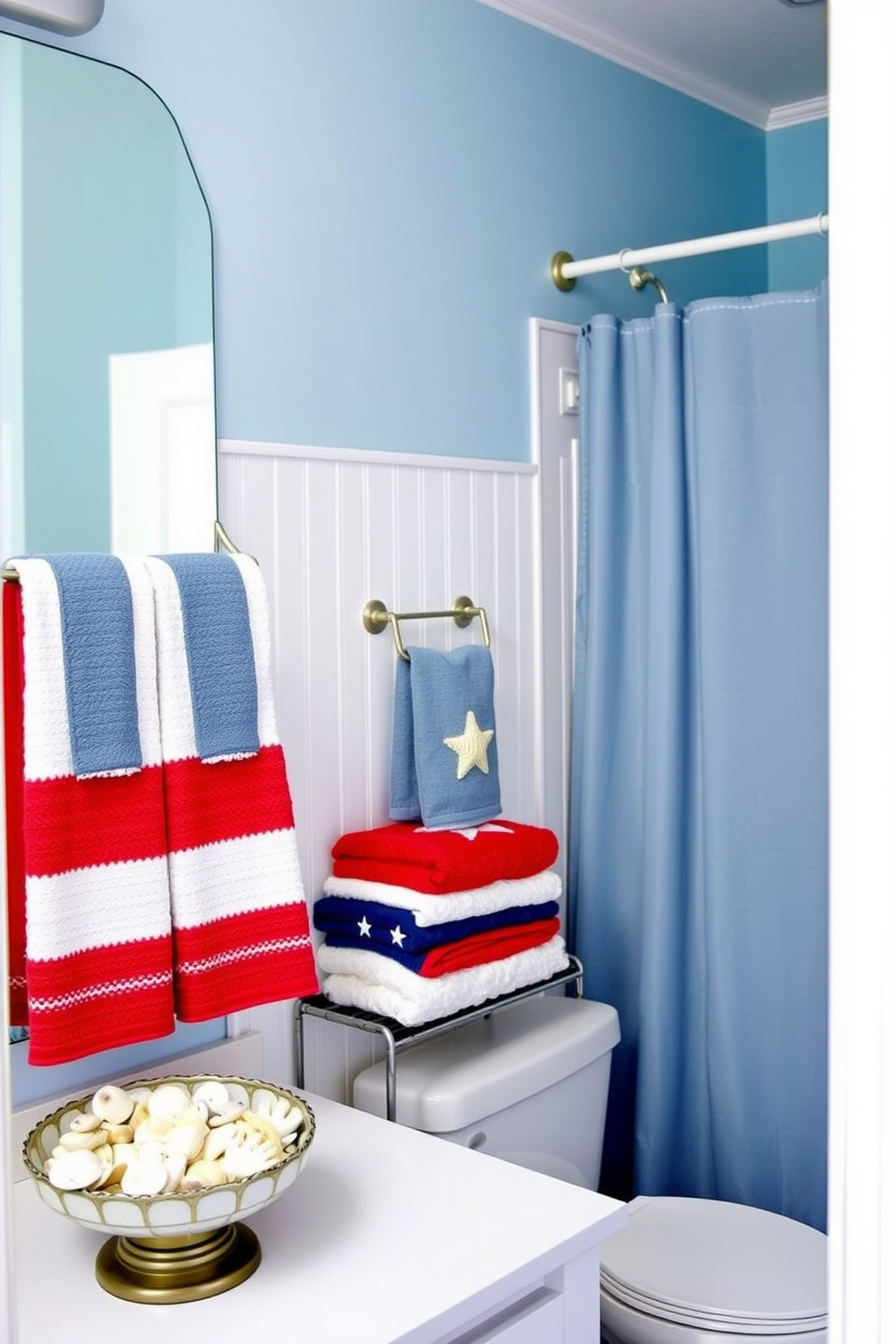 A serene coastal bathroom featuring soft blue walls and white beadboard paneling. Seashell accents are incorporated throughout, including a decorative bowl filled with assorted seashells on the countertop and a shower curtain adorned with a subtle seashell pattern. Labor Day themed decorations are tastefully arranged, with red, white, and blue towels neatly folded on a rack. A small flag banner is draped across the mirror, adding a festive touch to the relaxing space.