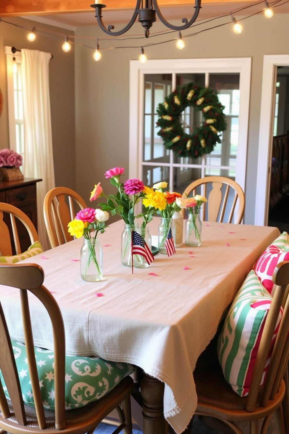 A cozy dining room setting for a Labor Day gathering. The table is adorned with a rustic tablecloth and mason jars filled with fresh flowers as casual drinkware. Chairs are arranged around the table, featuring colorful cushions that complement the seasonal decor. String lights are hung above, creating a warm and inviting atmosphere for guests.