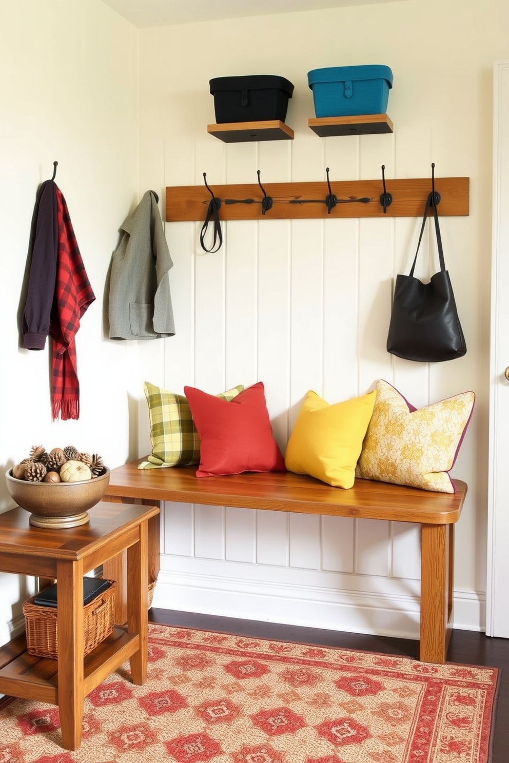 A cozy mudroom featuring a rustic wooden bench adorned with colorful cushions in shades of blue, yellow, and orange. The walls are painted a soft cream color, and hooks for coats and bags are mounted above the bench, creating a welcoming space. To the left of the bench, a small table holds a decorative bowl filled with seasonal items like pinecones and acorns. A patterned rug in earthy tones lies beneath the bench, adding warmth and texture to the room.