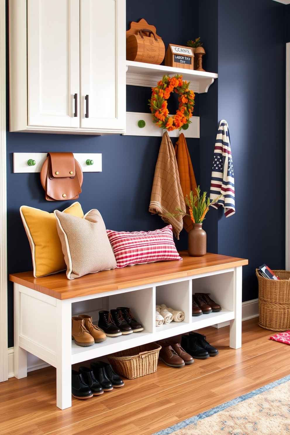 A sleek bench with integrated shoe storage occupies the entryway, offering a practical yet stylish solution for organizing footwear. The bench features a smooth wooden surface and is complemented by decorative cushions in warm, inviting colors. The mudroom is adorned with Labor Day-themed decor, including rustic accents and seasonal touches that celebrate the holiday. A bold accent wall in a deep navy hue contrasts beautifully with lighter cabinetry, creating a welcoming atmosphere.