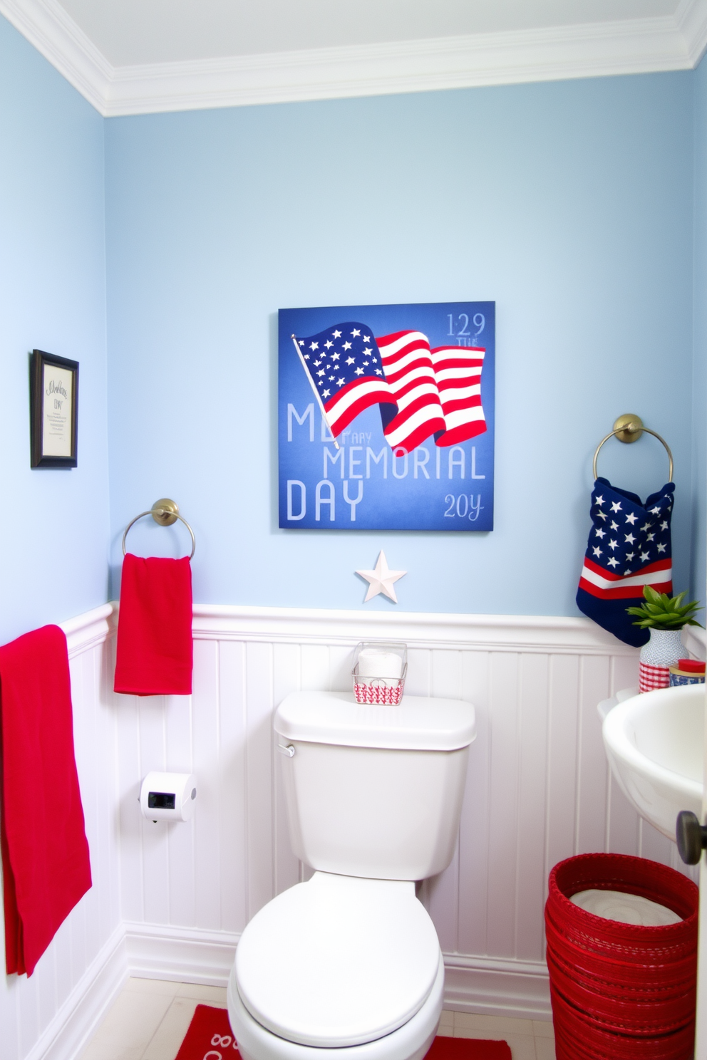 A patriotic themed bathroom featuring artwork above the toilet that celebrates Memorial Day. The walls are painted in a soft blue hue, complementing the red and white accents throughout the space.