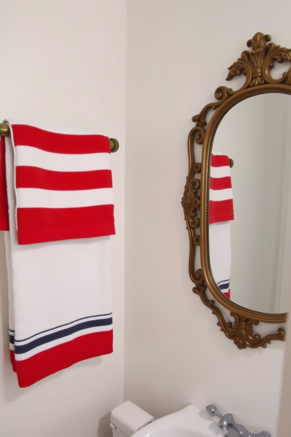 A festive bathroom setting featuring red white and blue towels neatly arranged on a wooden towel rack. The walls are painted in a soft white hue, and a decorative mirror with a vintage frame adds a touch of elegance to the space.