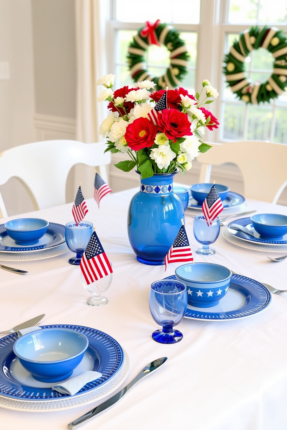 A charming dining table set for Memorial Day features blue and white ceramic dishware arranged neatly on a crisp white tablecloth. The table is adorned with small American flags and fresh flowers in a matching blue vase, creating a festive and patriotic atmosphere.