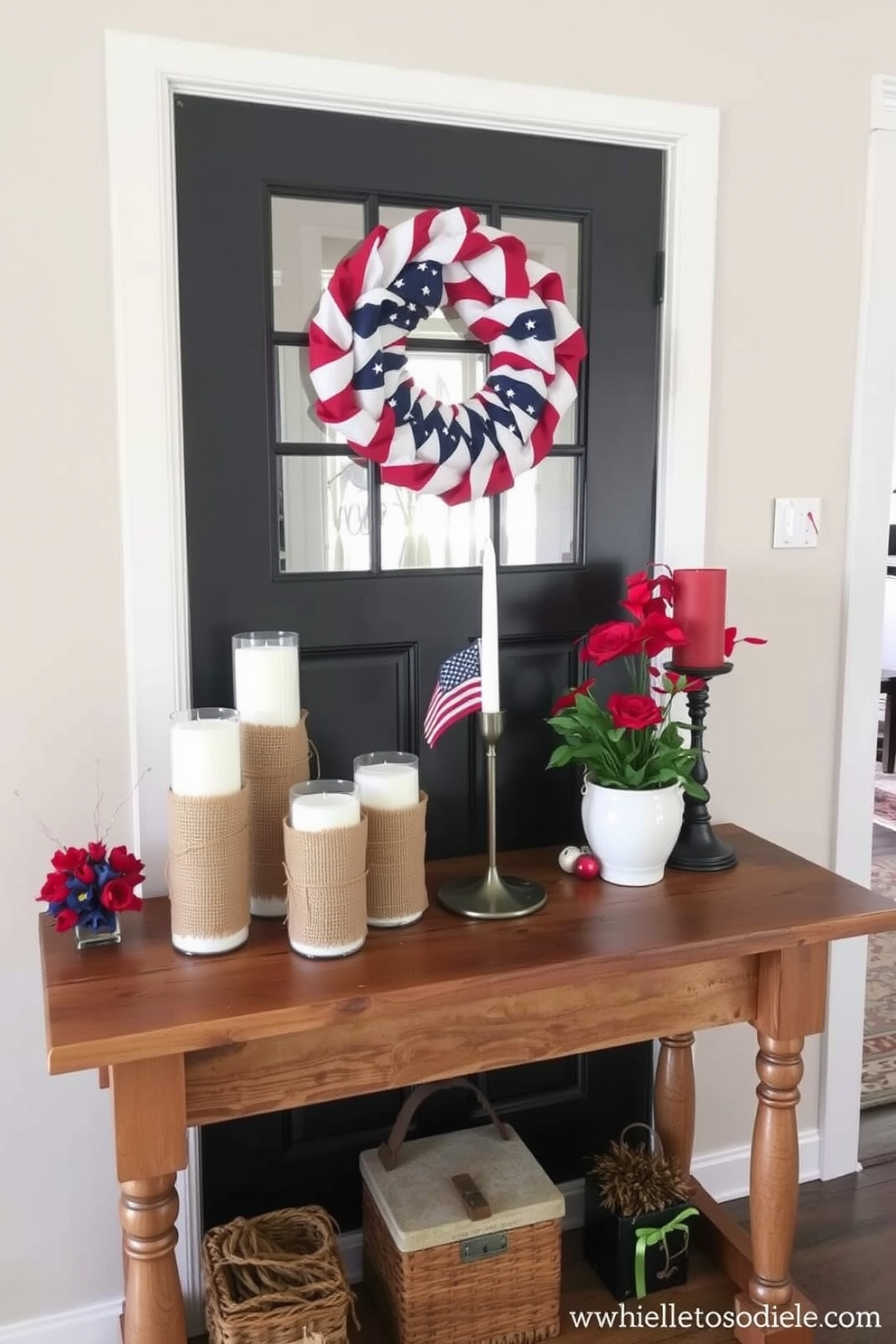 Candle holders wrapped in burlap are arranged on a rustic wooden console table. The entryway is adorned with red white and blue accents to celebrate Memorial Day.