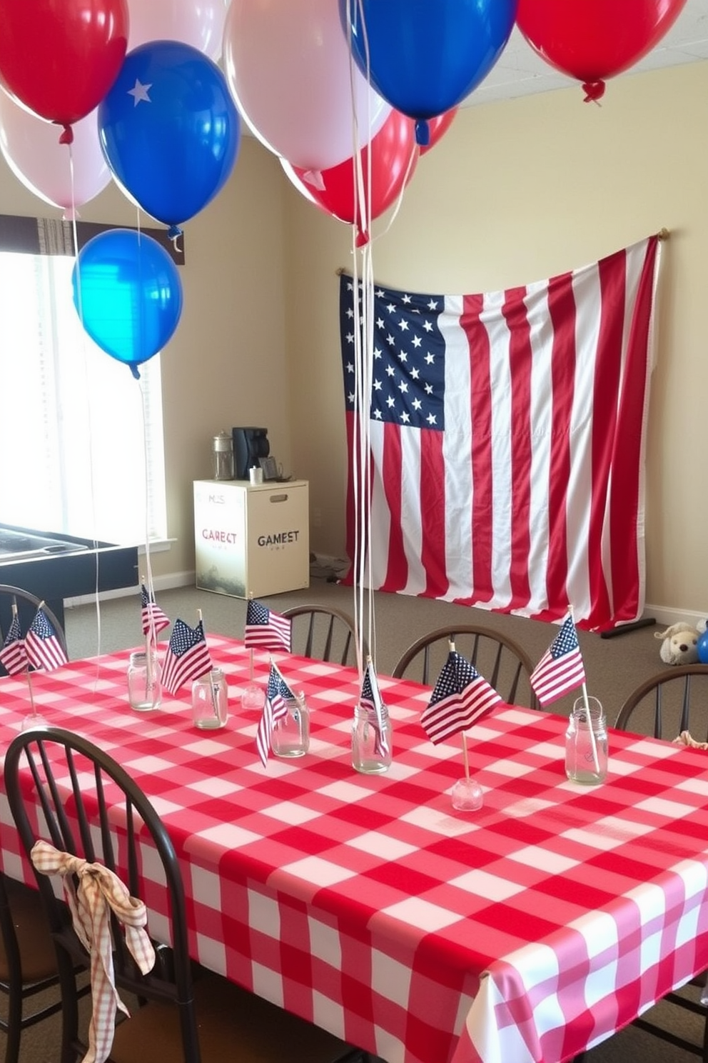 A festive game room setting adorned with star spangled banner table decorations. The table is covered with a red and white checkered tablecloth, and small American flags are placed in mason jars as centerpieces. Colorful balloons in red, white, and blue are tied to the chairs, creating a lively atmosphere. A backdrop featuring the stars and stripes is hung on the wall, adding to the patriotic theme.