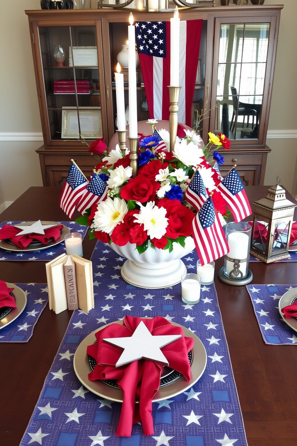 A patriotic themed table centerpiece featuring a combination of red white and blue elements. The centerpiece includes a large decorative bowl filled with fresh flowers in these colors surrounded by small American flags and candles. The table is set with star patterned table runners and matching placemats. To enhance the festive atmosphere a few vintage books and rustic lanterns are incorporated into the design.