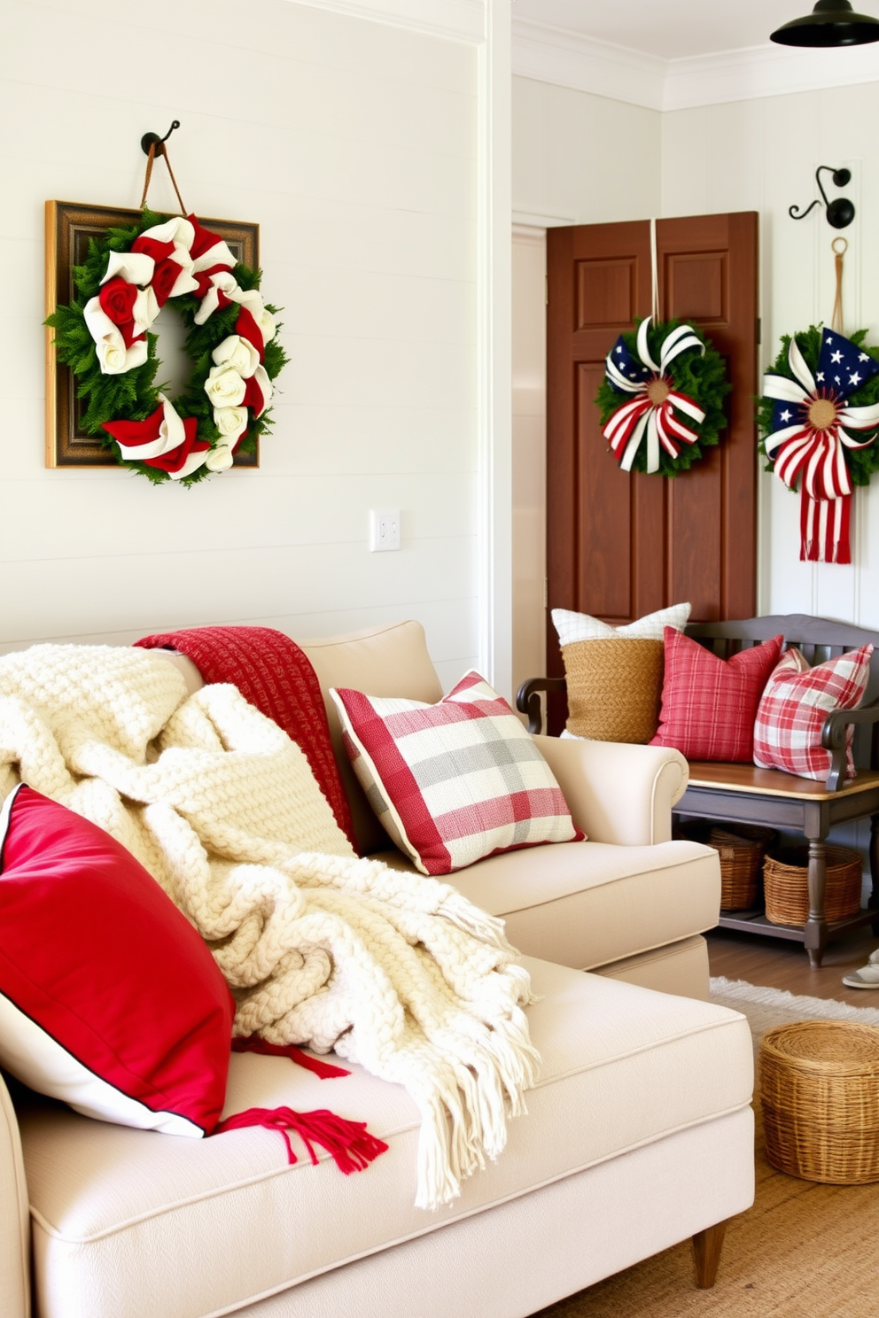 Layered textiles create a cozy atmosphere with plush throw blankets draped over a soft sectional sofa. Decorative pillows in varying textures and patterns add depth and comfort to the seating area. For Memorial Day, the mudroom is adorned with red, white, and blue accents that celebrate the holiday. A vintage bench is flanked by woven baskets for storage, and a patriotic wreath hangs on the door to welcome guests.