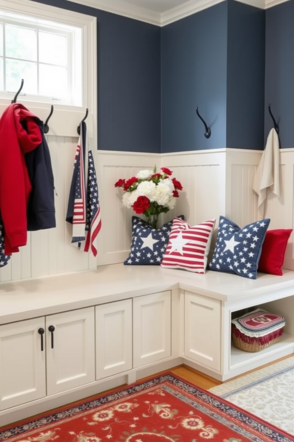 A functional mudroom island designed for extra space features a large central bench with built-in storage underneath. The surrounding walls are adorned with hooks for coats and bags, while a stylish rug adds warmth to the space. For Memorial Day, the mudroom is decorated with red white and blue accents. Fresh flowers in a vase and patriotic-themed cushions on the bench create a festive and welcoming atmosphere.